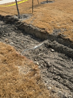 Straight retaining-wall footing trenches and layout stakes at the Riesel-area site