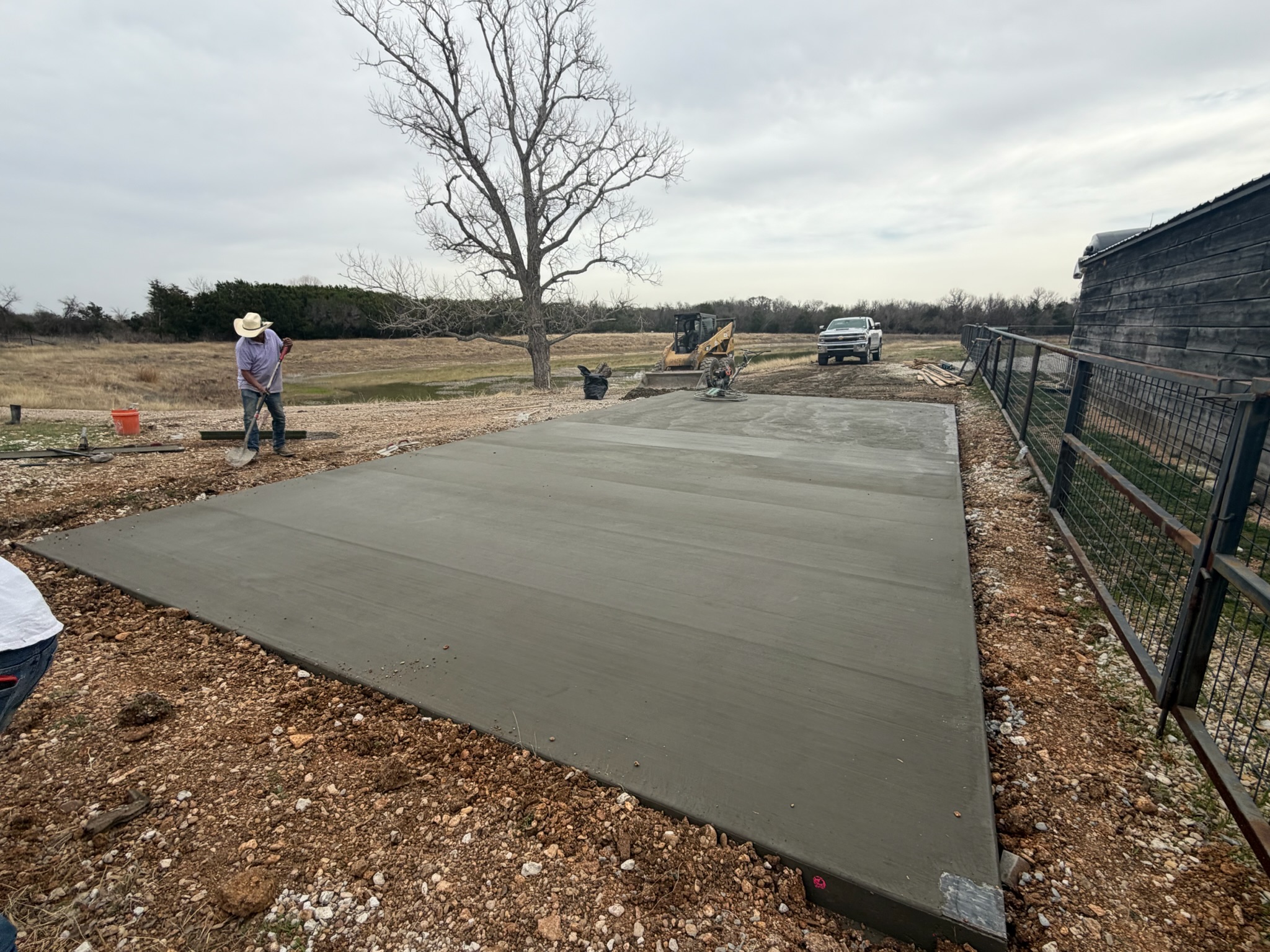 Finished troweled Magnolia RV pad beside the fence and outbuilding