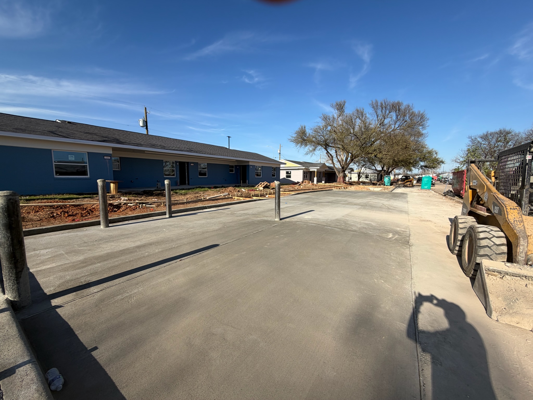Finished parking-area concrete with curb lines and protected bollards at Melody Grove